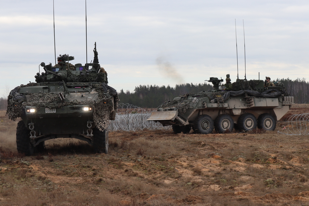 Kanadští ženisté na vozidlech LAV při průjezdu průchodem v drátěném zátarasu.