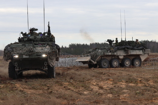 Kanadští ženisté na vozidlech LAV při průjezdu průchodem v drátěném zátarasu.