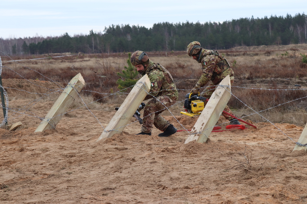 Italští ženisté překonávají český nevýbušný zátaras za pomoci pneumatických kleští.